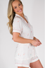 A woman wearing a white short sleeve and short pajama set with text and confetti print