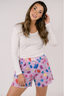 Model with white long sleeve shirt and purple boxer short with multicolor pattern.
