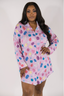 A woman modeling a purple sleep dress with a jewel pattern. The dress has a classic PJ silhouette with long sleeves and a button-up front.