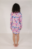 A woman modeling a purple sleep dress with a jewel pattern. The dress has a classic PJ silhouette with long sleeves and a button-up front.