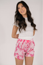 A person wearing a white t-shirt and pink boxer shorts with a bow print.