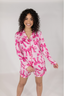 A female model wearing a long sleeve and short pajama set with a pink bubblegum bow print.