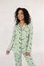 A woman wearing a long sleeve and pant pajama set with a green background and champagne glass print.