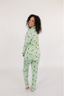 Model showing the backside of the light green matching pajama set with yellow champagne bottles.