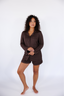 Model standing in chocolate brown pajama with long sleeves and shorts.