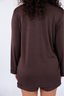 Model standing in chocolate brown pajama with long sleeves and shorts.