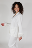 A woman modeling a white feather long sleeve and cropped pant pajama set with detachable feather cuffs on the wrists and ankles.