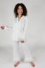 A woman modeling a white feather long sleeve and cropped pant pajama set with detachable feather cuffs on the wrists and ankles.