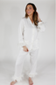 A woman modeling a white feather long sleeve and cropped pant pajama set with detachable feather cuffs on the wrists and ankles.
