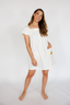 Woman wearing a white dress with a pocket on a plain background