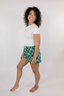 Model standing in white t-shirt with green shorts with geometric bow pattern.