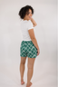 Model standing in white t-shirt with green shorts with a geometric bow pattern.