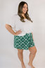 Model standing in white t-shirt with green boxer shorts with geometric bow pattern.