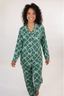 A woman wearing a long sleeve and pant pajama set with an evergreen bow print.