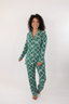 Model standing in green matching pajama set with geometric bow pattern.