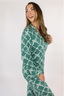 Model standing in green matching pajama set with geometric bow pattern.