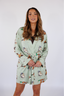 Model standing in short robe that is green with ducks.