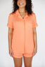 Woman wearing a peach-colored pajama set on a white background