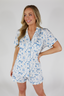 A woman modeling a short sleeve and short pajama set with a white and blue Happily Ever After print.