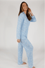 A woman wearing a long sleeve blue pajama top with a bow pattern and matching pants