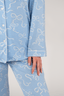 A woman wearing a long sleeve blue pajama top with a bow pattern and matching pants