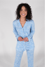 A woman wearing a long sleeve blue pajama set with a bow pattern.