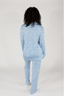A woman wearing a long sleeve blue pajama top with a bow pattern and matching pants