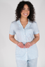 A woman wearing a short sleeve and cropped pant pajama set in sky blue with a bow pattern.