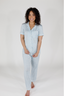 A woman wearing a short sleeve and cropped pant pajama set in sky blue with a bow pattern.