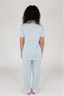 A woman wearing a short sleeve and cropped pant pajama set in sky blue with a bow pattern.