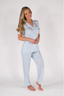 A woman wearing a short sleeve and cropped pant pajama set in sky blue with a bow pattern.
