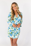 A woman smiling and wearing a blue floral short robe with long sleeves.
