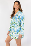 A woman smiling and wearing a blue floral short robe with long sleeves.
