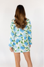 A woman smiling and wearing a blue floral short robe with long sleeves.