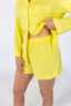 A woman wearing a long sleeve and short yellow pajama set.