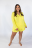 A woman wearing a long sleeve and short yellow pajama set.