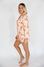 Woman wearing a patterned outfit with orange designs on a white background