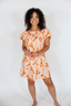 Woman wearing an orange patterned dress on a white background