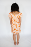 Woman wearing an orange and white patterned dress on a white background