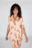Woman wearing a pajama set with orange lobster print on a white background