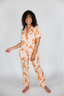 Woman wearing a peach-colored pajama set with orange patterns on a white background