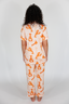 Person wearing a matching orange and white pajama set with a pattern on a plain background