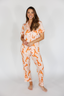 Woman wearing a matching orange and white pajama set on a plain background