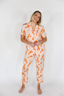 Woman wearing a matching orange and white pajama set on a white background