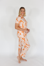 Woman wearing a matching orange and beige pajama set on a white background
