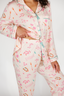 Person wearing a pink floral pajama set on a white background