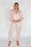 Woman wearing a pink pajama set with cartoon designs on a white background