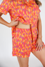 Person wearing a bright orange and pink patterned outfit on a white background