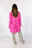 A woman wearing a pink short robe with a tie waist, made from a soft and comfortable fabric.