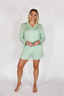 Woman wearing a light green pajama set on a white background